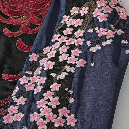 Navy sleeve cherry blossom branch embroidery detail beside red chrysanthemum, smooth satin.