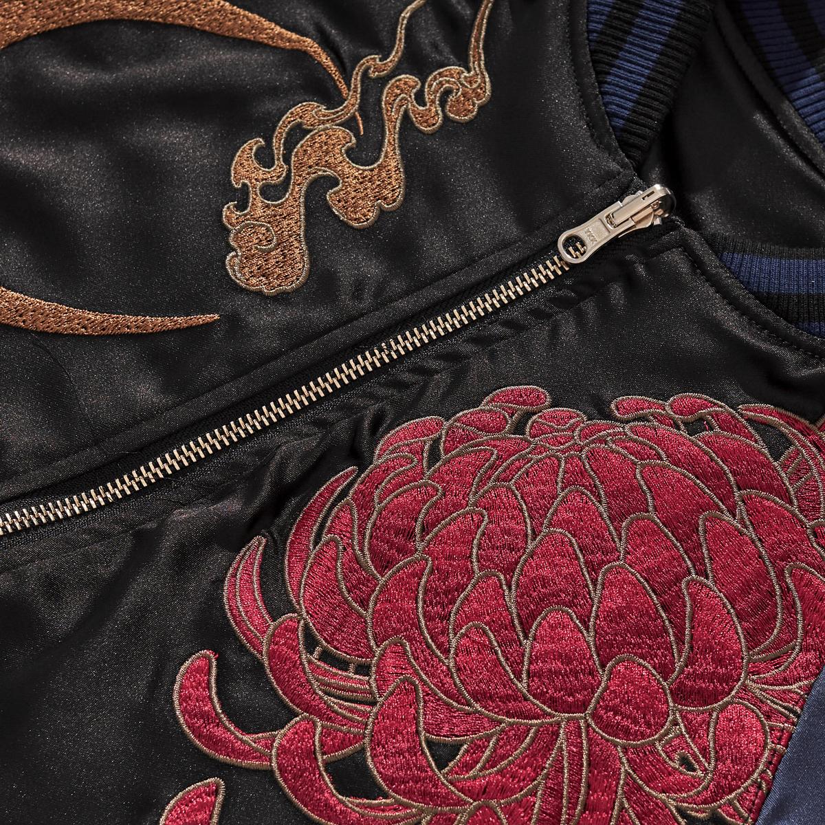 Zipper area close-up featuring bronze crescent and bold red chrysanthemum stitching, navy.