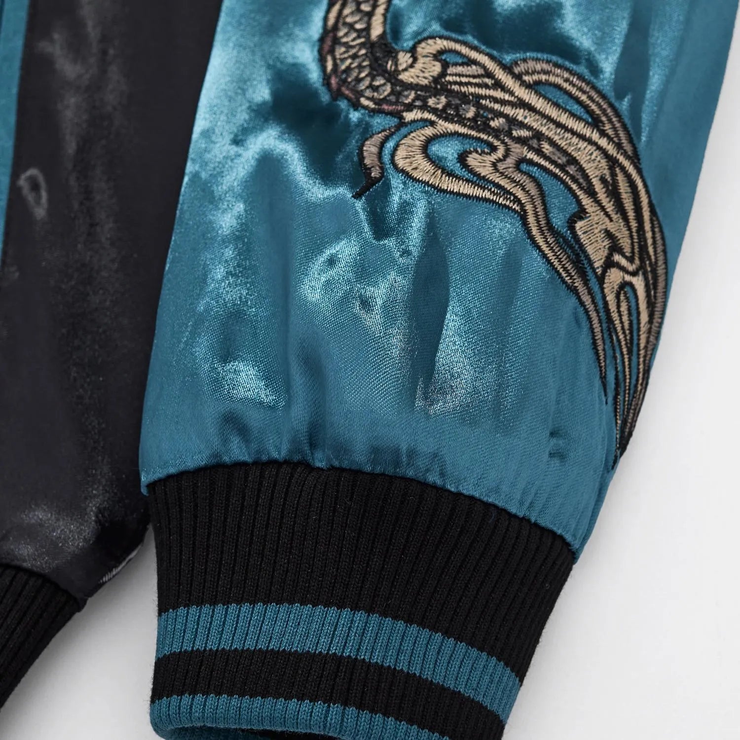 Close-up of the elastic ribbed cuff on the blue satin sleeve with dragon tail embroidery.