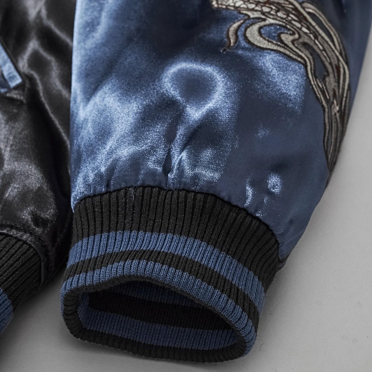 Close-up of navy satin sleeve and striped ribbed cuff on Storm Dragons & Peony dragon bomber jacket.