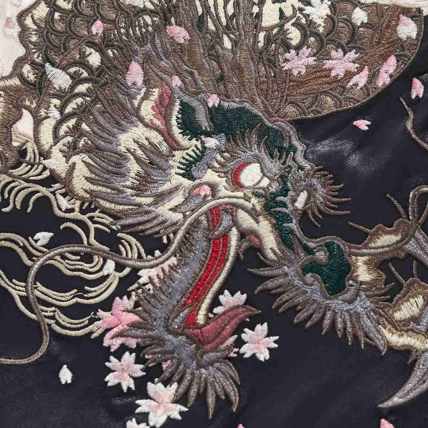 Macro detail of sakura dragon head embroidery with pink cherry blossom petals on Twin Dragons & Sakura sukajan jacket.