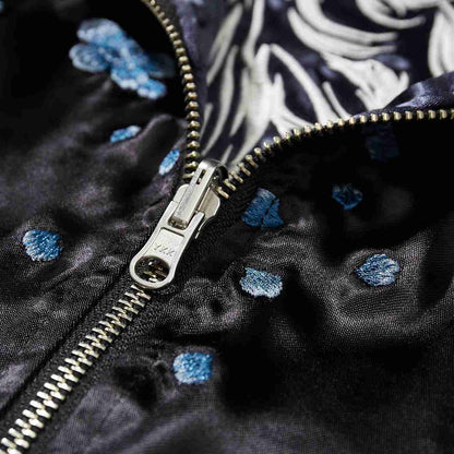 YKK metal zipper close-up with scattered blue blossom embroidery.