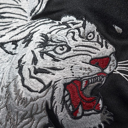 White tiger head embroidery close-up with layered stitches and red accents